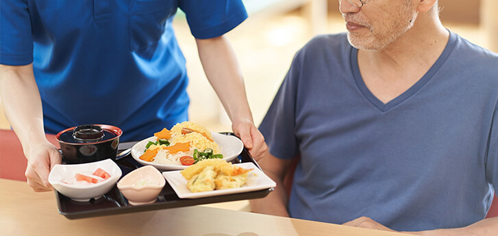 お食事を運ぶ介護士